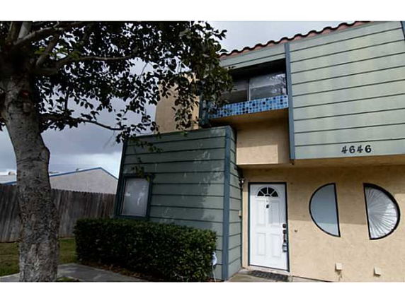 Front view of a two-story house with green siding and circular windows.