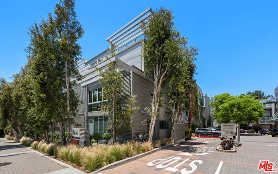 Front view of a modern multi-story building with large windows and vertical metal siding.