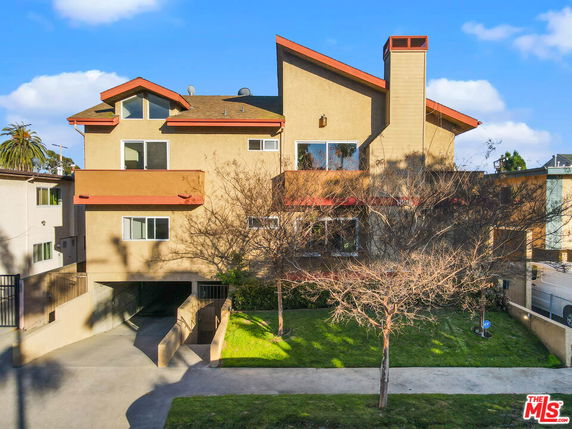 Front view of a multi-story house with a unique roof design and a gated garage entrance.