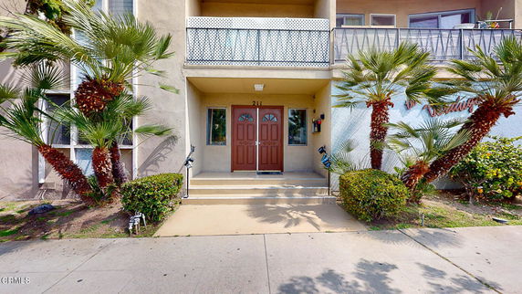 Front view of a residential building with a small staircase leading to double entrance doors and a balcony above.
