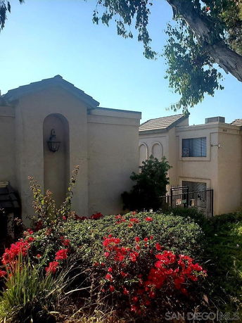 Front view of a two-story house with a stucco exterior and arched entryway.