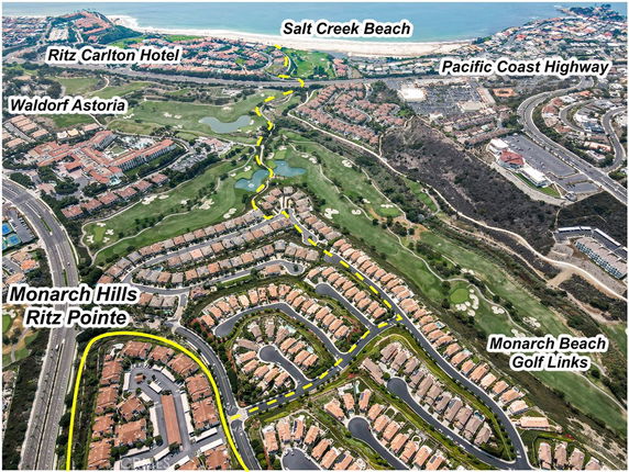 Aerial panoramic view of a residential area with hotels, golf courses, and a beach in the background.