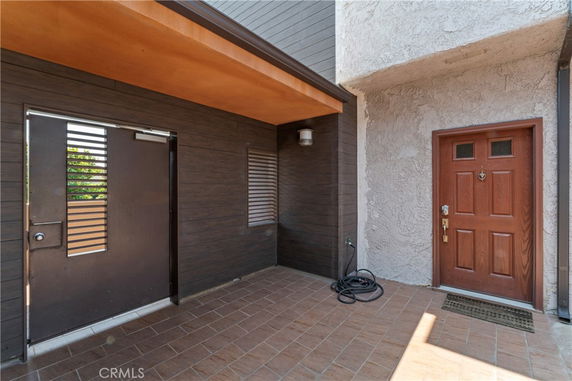 Front view of an entryway with a wooden door and tiled flooring.