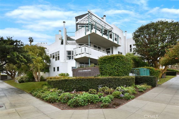 Front view of a modern multi-story building with balconies and white exterior walls.