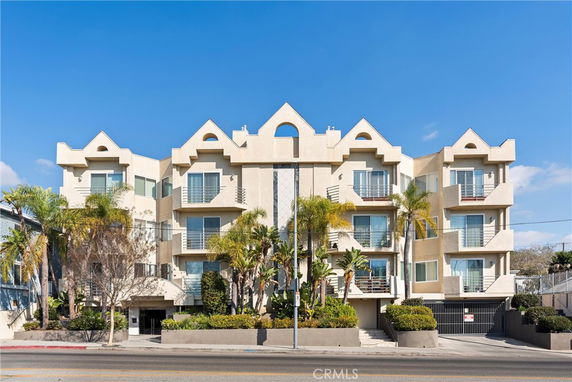 Front view of a multi-story apartment building with balconies and modern architectural design.