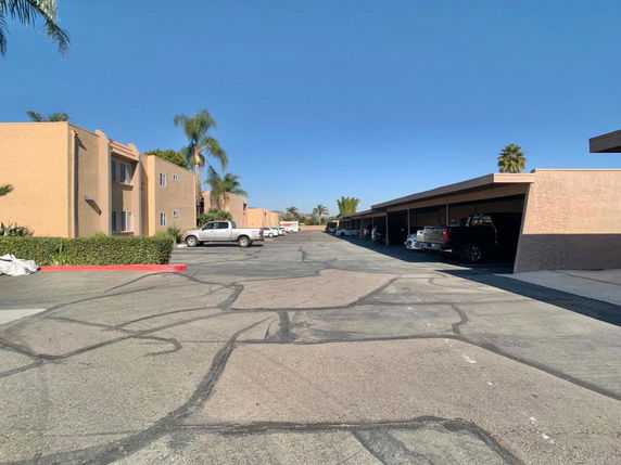View of an outdoor covered parking area next to apartment buildings.
