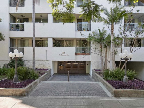 Front view of a multi-story building with balconies and glass doors.