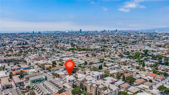 Wide aerial view showcasing a cityscape with numerous buildings and the coastline in the distance.