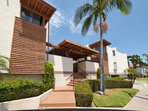 Front view of a multi-story building with wooden accents and a sloped entryway.