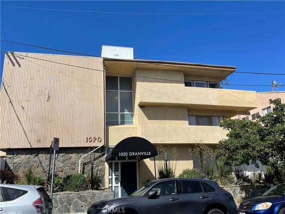 Front view of a multi-story building with a flat roof and a rounded awning over the entrance.