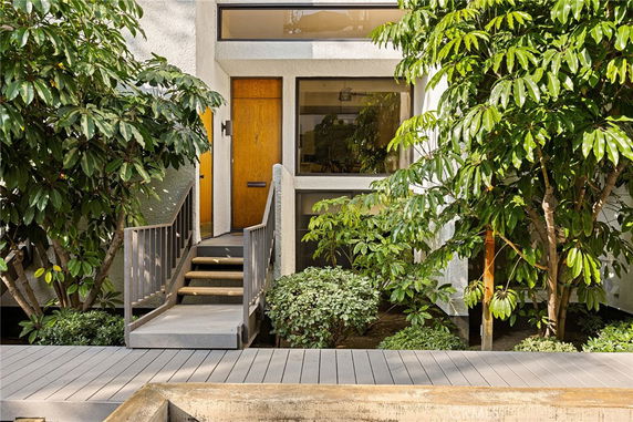 Front view of a house with a wooden door and surrounding greenery.