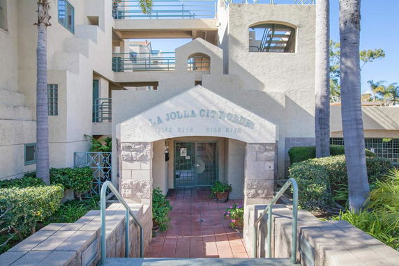 Front view of a multi-story building entrance with stone columns and arched details.