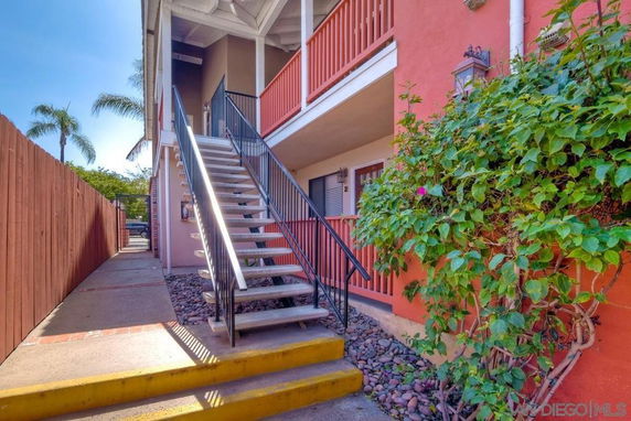 Front view of a two-story building with an exterior staircase and orange facade.