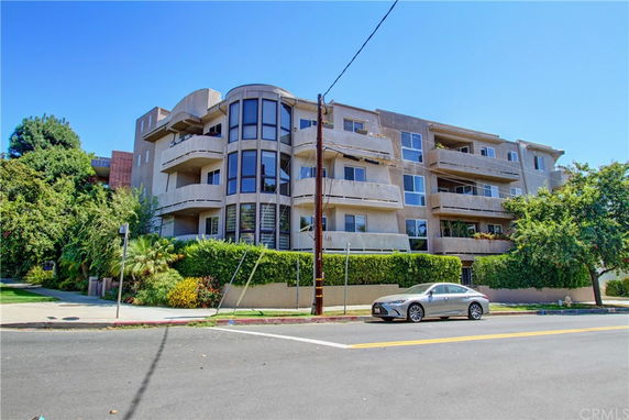 Front view of a multi-story apartment building with balconies and large windows.
