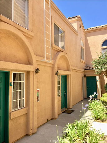 Front view of a two-story house with arched windows and green doors.