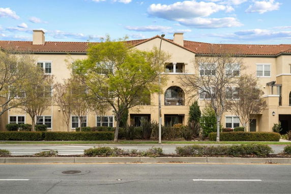 Front view of a multi-story building with a tile roof and beige facade.