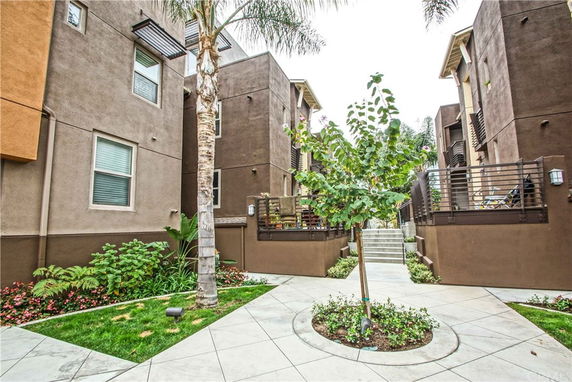 Front view of a multi-story apartment building with brown exterior walls and small landscaped area.