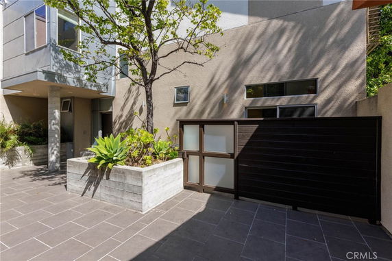 Front view of a modern house with a planter and a wooden gate.