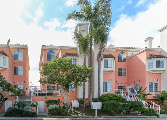 Front view of a multi-story building with pink exterior, large windows, and staircases leading to entrances.