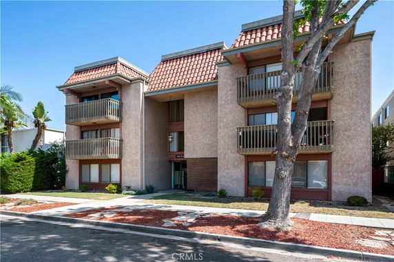 Front view of an apartment building with balconies and a tiled roof.