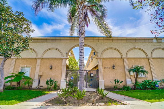 Front view of a building with an arched entrance and palm trees.