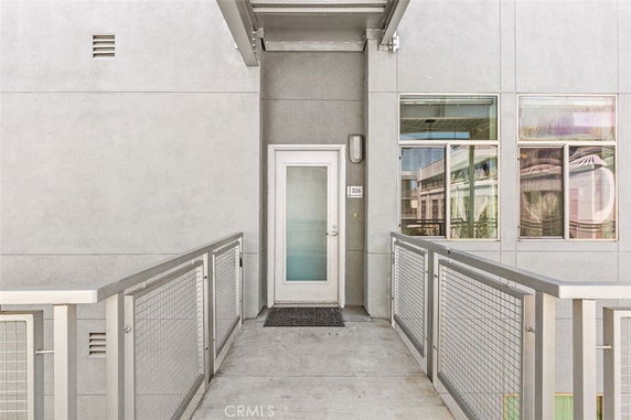 Front view of a modern building entrance with a metal railing and glass windows.
