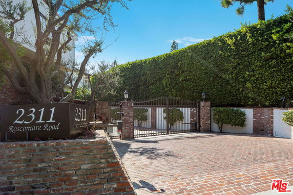 Front view of a building with a brick driveway and gated entrance.