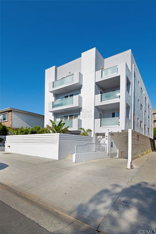 Front view of a multi-story building with balconies and a gated entrance.
