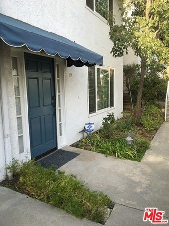 Front view of a house with a blue door and awning.