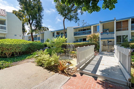 Front view of a multi-story residential building with balconies and a walkway.