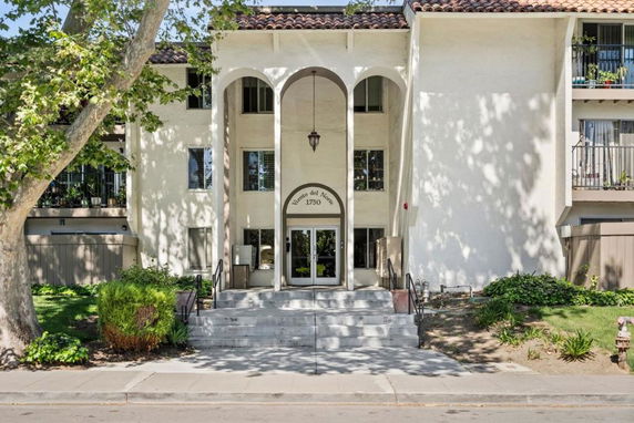 Front view of a multi-story residential building with arched entrance and balconies.