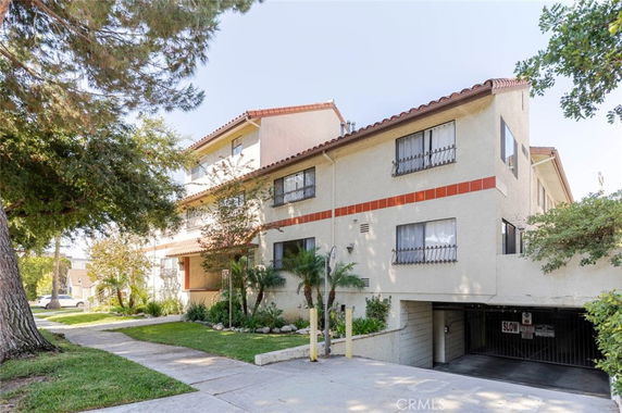 Front view of a multi-story residential building with a gated parking area.