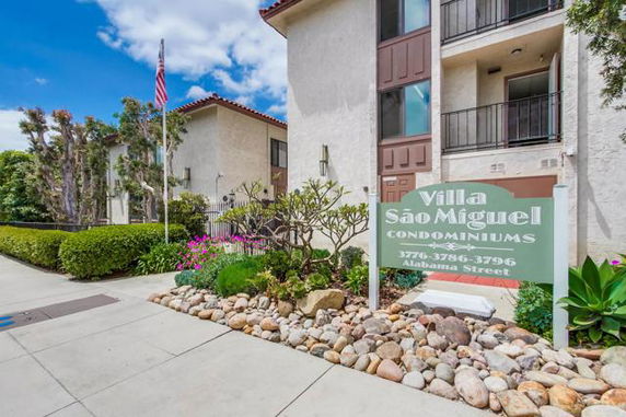 Front view of Villa Sao Miguel Condominiums building with a sign and manicured landscaping.