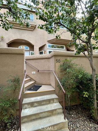 Front view of a multi-story house with a staircase leading to the entrance.