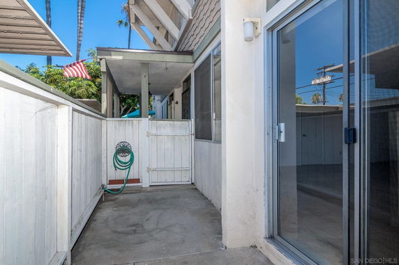 Outdoor area with a white fence and a sliding glass door.