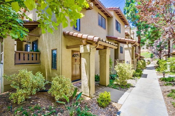 Front view of a multi-story townhouse with a pathway and landscaped area.