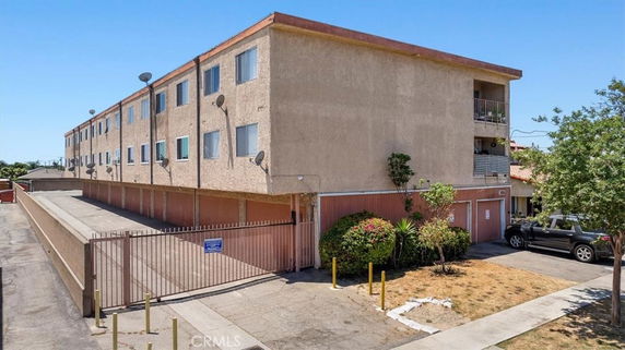Front view of a three-story apartment building with gated parking area.