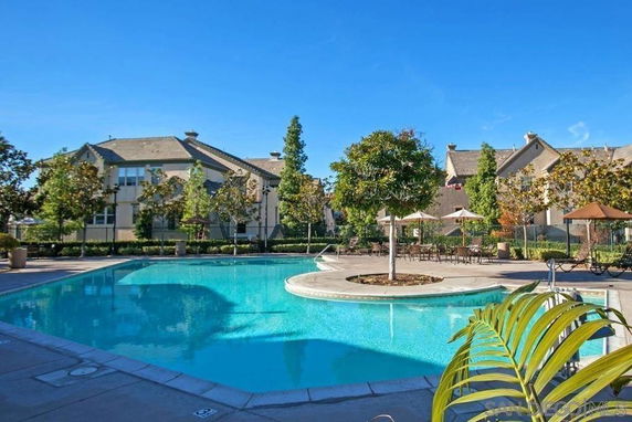 Outdoor swimming pool area with surrounding trees and buildings.