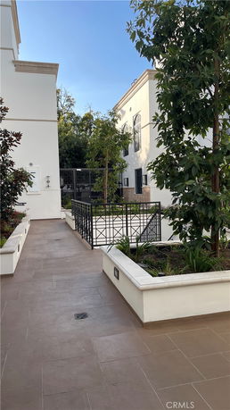 Side view of a building with a tiled walkway and greenery.