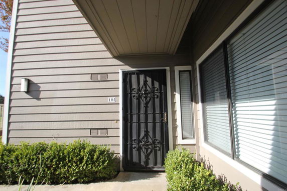Front view of a house entry with a decorative iron security door and adjacent windows with blinds.