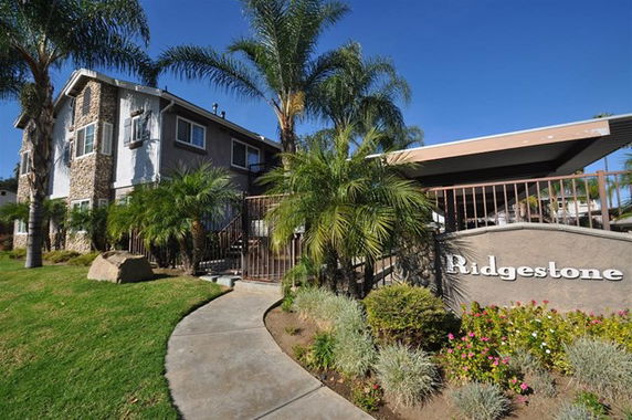 Front view of a two-story building with stone and siding exterior and palm trees in the landscaping.