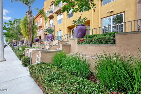 Front view of a multi-story building with stairway access and large planters.