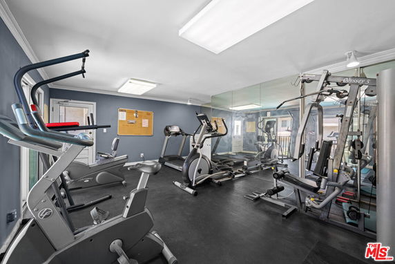 Indoor gym area with various exercise equipment and mirrored wall.