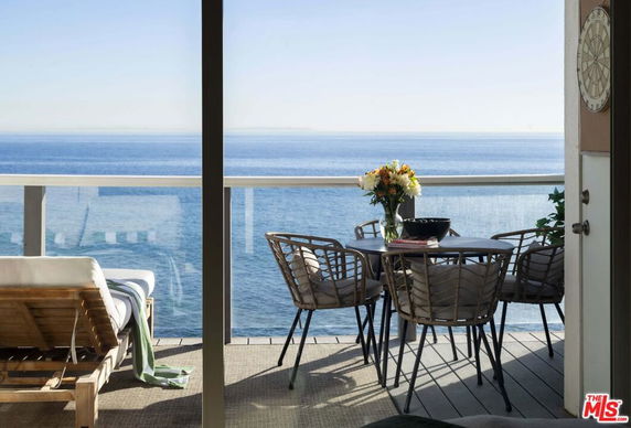 Outdoor seating area with a table and chairs overlooking the ocean view.