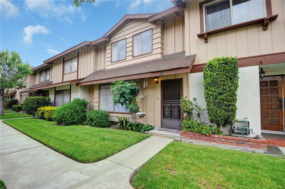 Front view of a two-story townhouse with a landscaped front yard.