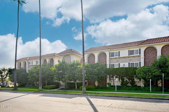 Front view of a multi-story residential building with arched windows and a tiled roof.