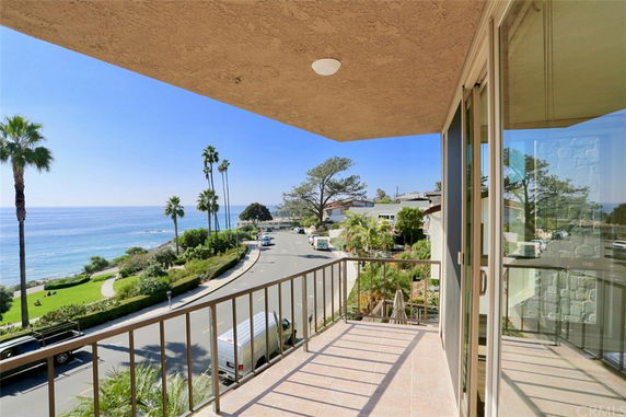 Balcony view overlooking a scenic coastline and nearby street.