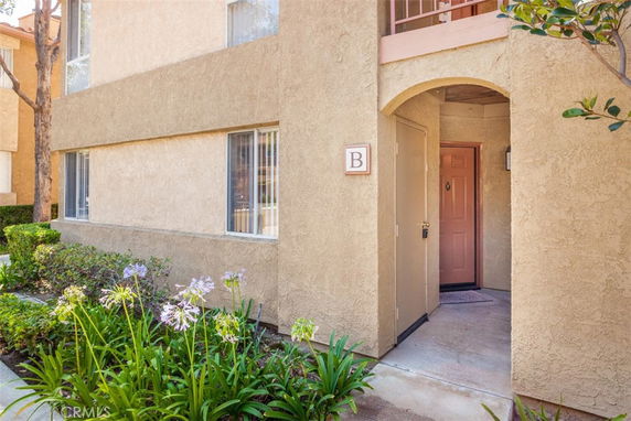 Exterior view of a building entrance with an arched doorway and a pink door.