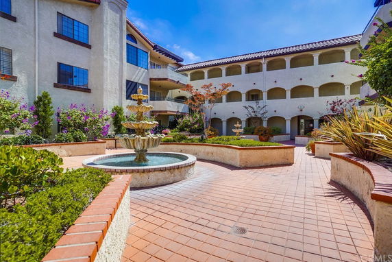 Front view of a multi-story building with a courtyard and a fountain.