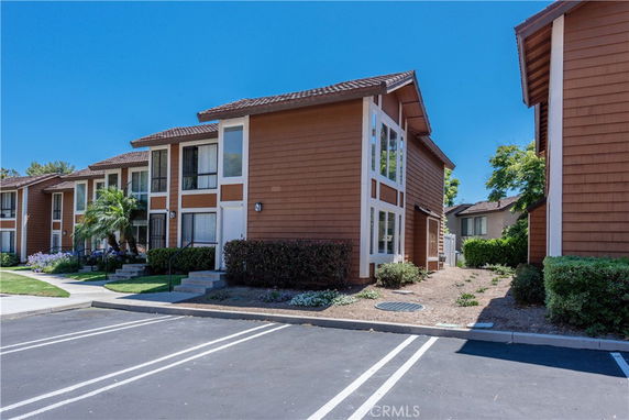 Front view of a two-story residential building with brown siding and large windows.